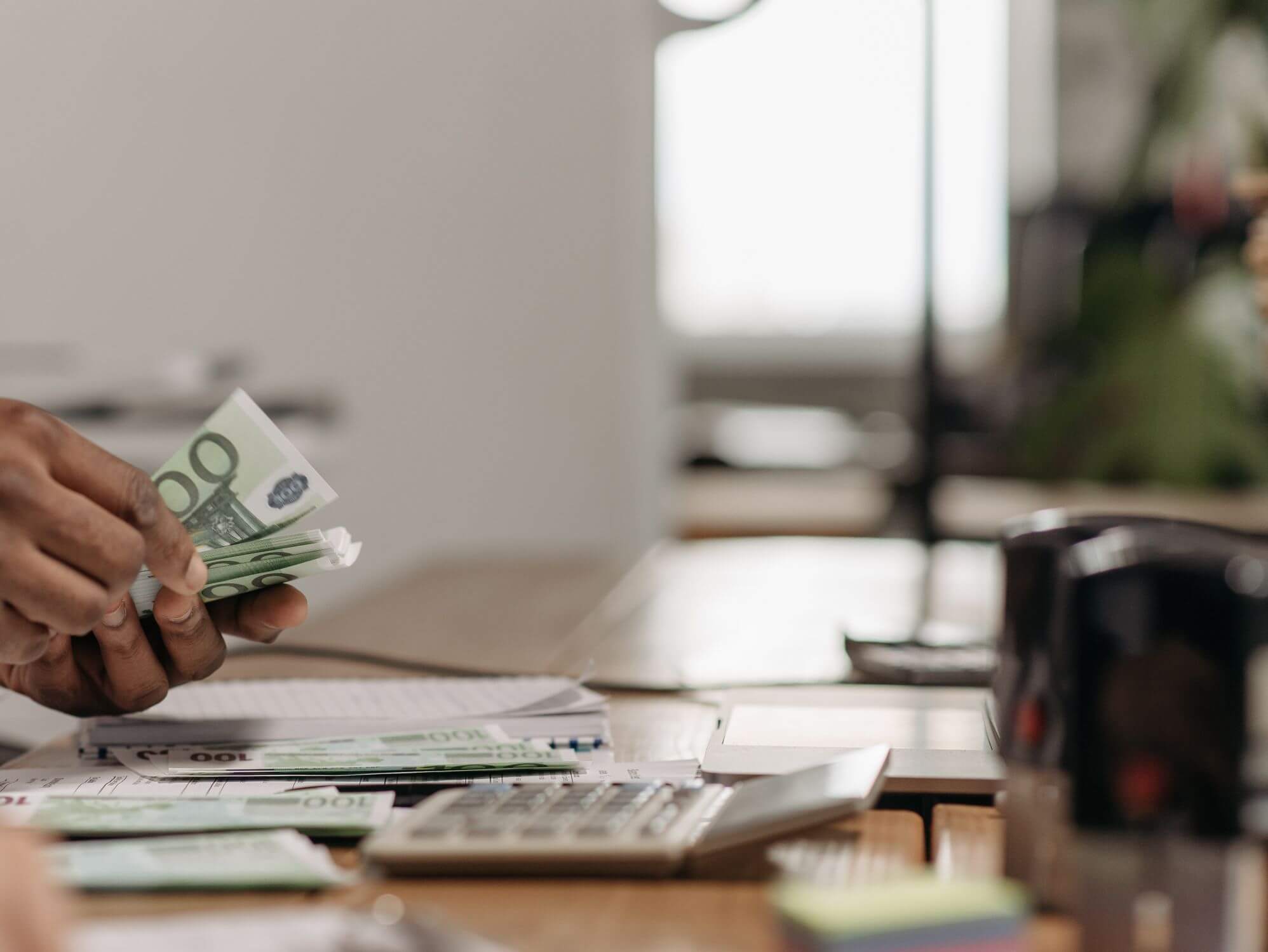 Persona revisant documents i calculadora il·lustrant com detectar si els teus hàbits financers estan perjudicant el teu pressupost